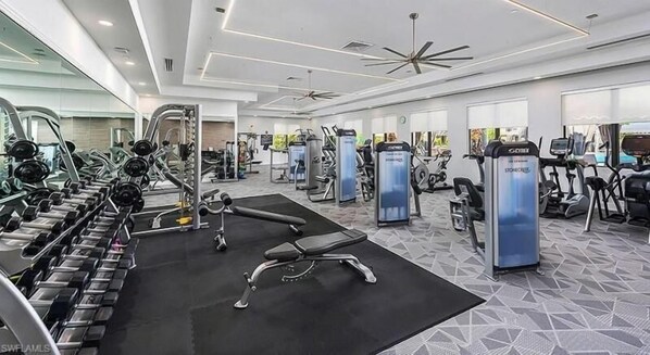 Un gimnasio moderno con diversos equipos de ejercicio, incluyendo cintas de correr, elípticas y estaciones de pesas.