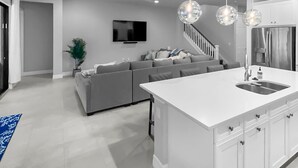 A modern kitchen with a central island, white cabinetry, and pendant lighting.