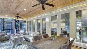 Une pièce spacieuse avec une grande table à manger, des meubles en osier et un ventilateur de plafond.