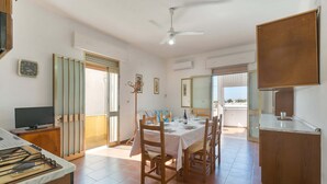 Un coin repas avec une table dressée pour quatre personnes, un téléviseur posé sur un meuble et un ventilateur de plafond.