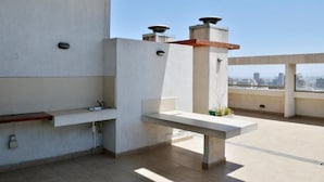 Une terrasse sur le toit avec un banc en béton, un petit évier et une vue sur la ville.
