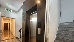 A modern elevator with a digital display, a staircase, and a hallway with a wooden floor and a door at the end. - Motel Phuong Linh (Da Nang)