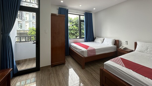 A hotel room with two beds, a wardrobe, a bedside table with a phone, and a window with curtains. - Motel Phuong Linh (Da Nang)