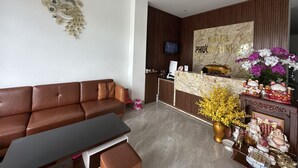 A hotel reception area with a brown leather sofa, a reception desk, and a wall-mounted clock. - Motel Phuong Linh (Da Nang)