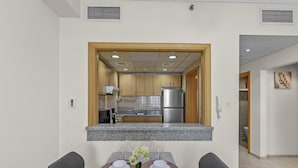 A modern kitchen with granite countertops, stainless steel appliances, and wooden cabinets. - Pure Living - Cozy Apartment With Balcony In Silicon Oasis (Dubai)
