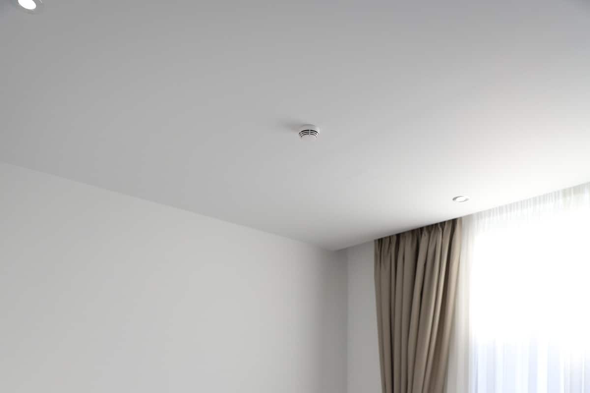 Quarto de hotel moderno com uma cama grande, cabeceira e janela com cortinas.