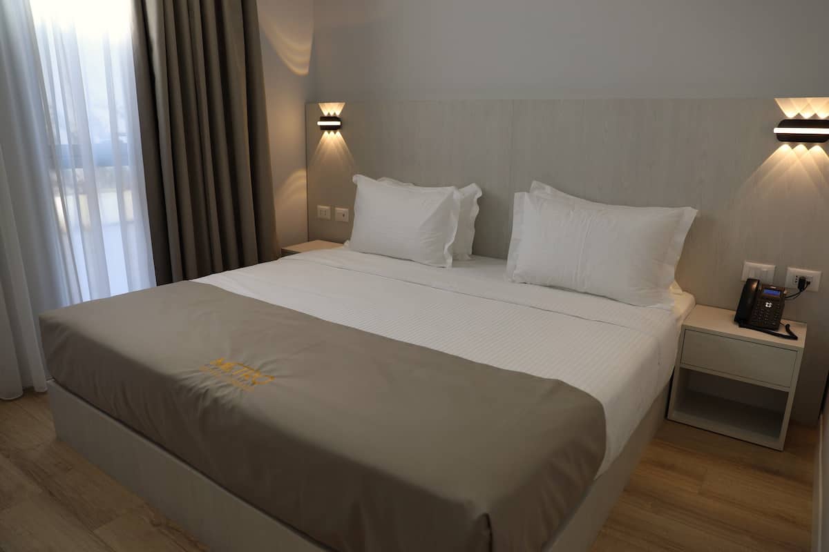 Quarto de hotel com cama, mesas de cabeceira e telefone.