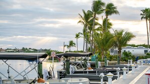 A marina with boats docked, a covered boat, and a waterway with palm trees in the background. - Sugarloaf Key Hotel at KOA Resort (Summerland Key)
