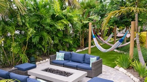 An outdoor patio with wicker furniture, a fire pit, and a hammock. - Sugarloaf Key Hotel at KOA Resort (Summerland Key)