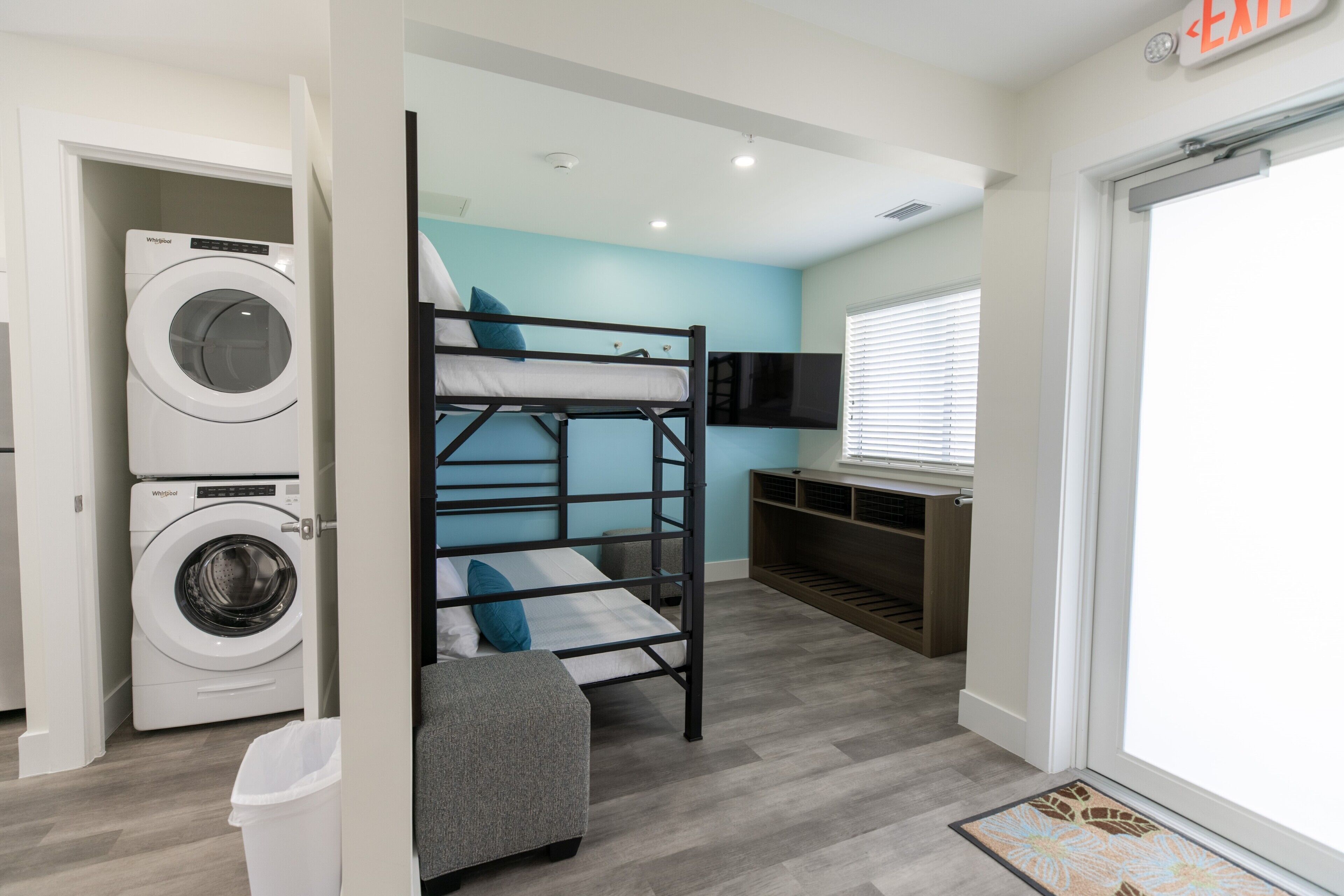 A compact room with bunk beds, a washing machine, and a television.
