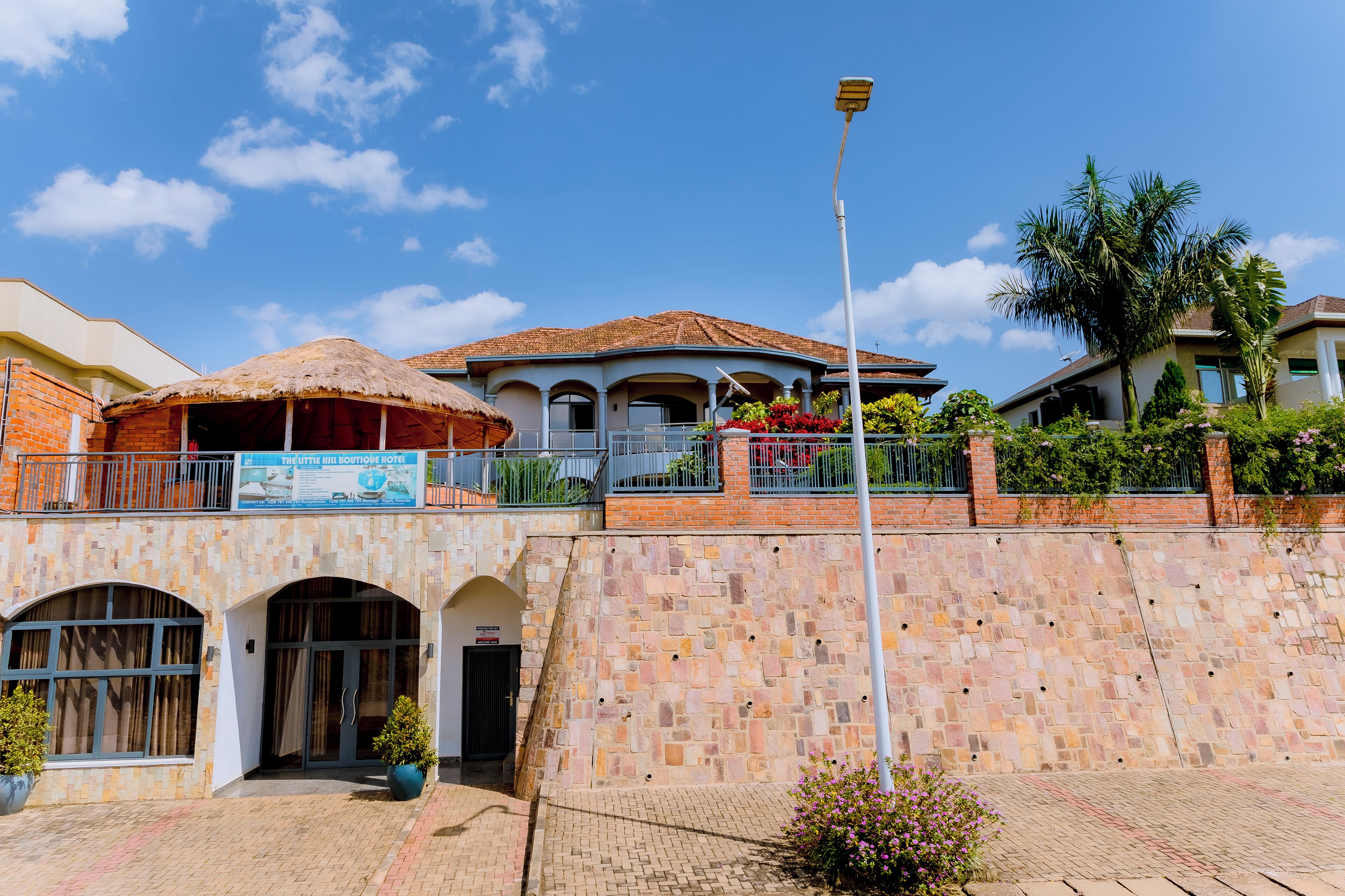 Un hotel con estructura de techo de paja, fachada de piedra y un balcón con macetas.