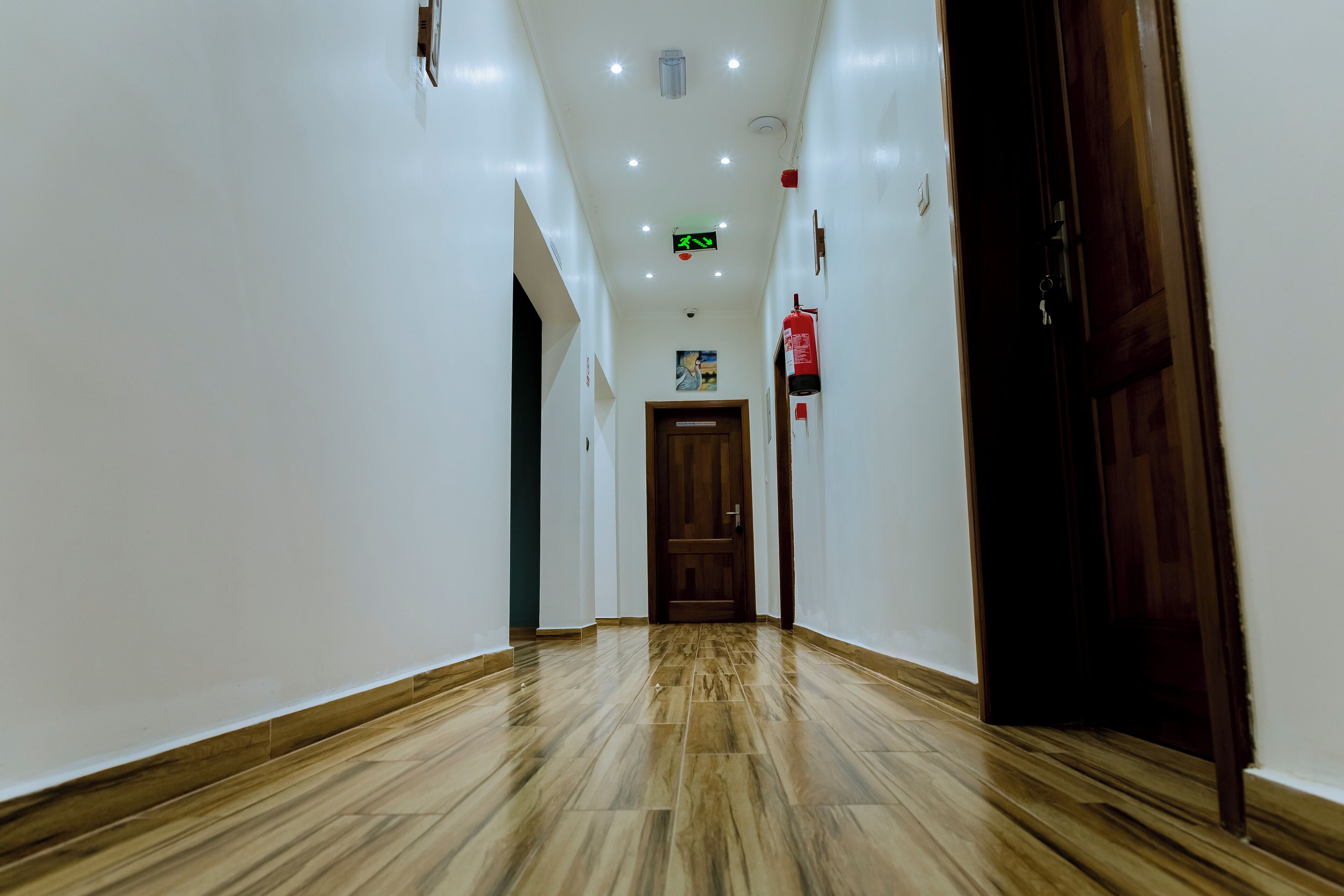 A hallway with wooden flooring, white walls, and a wooden door at the end.