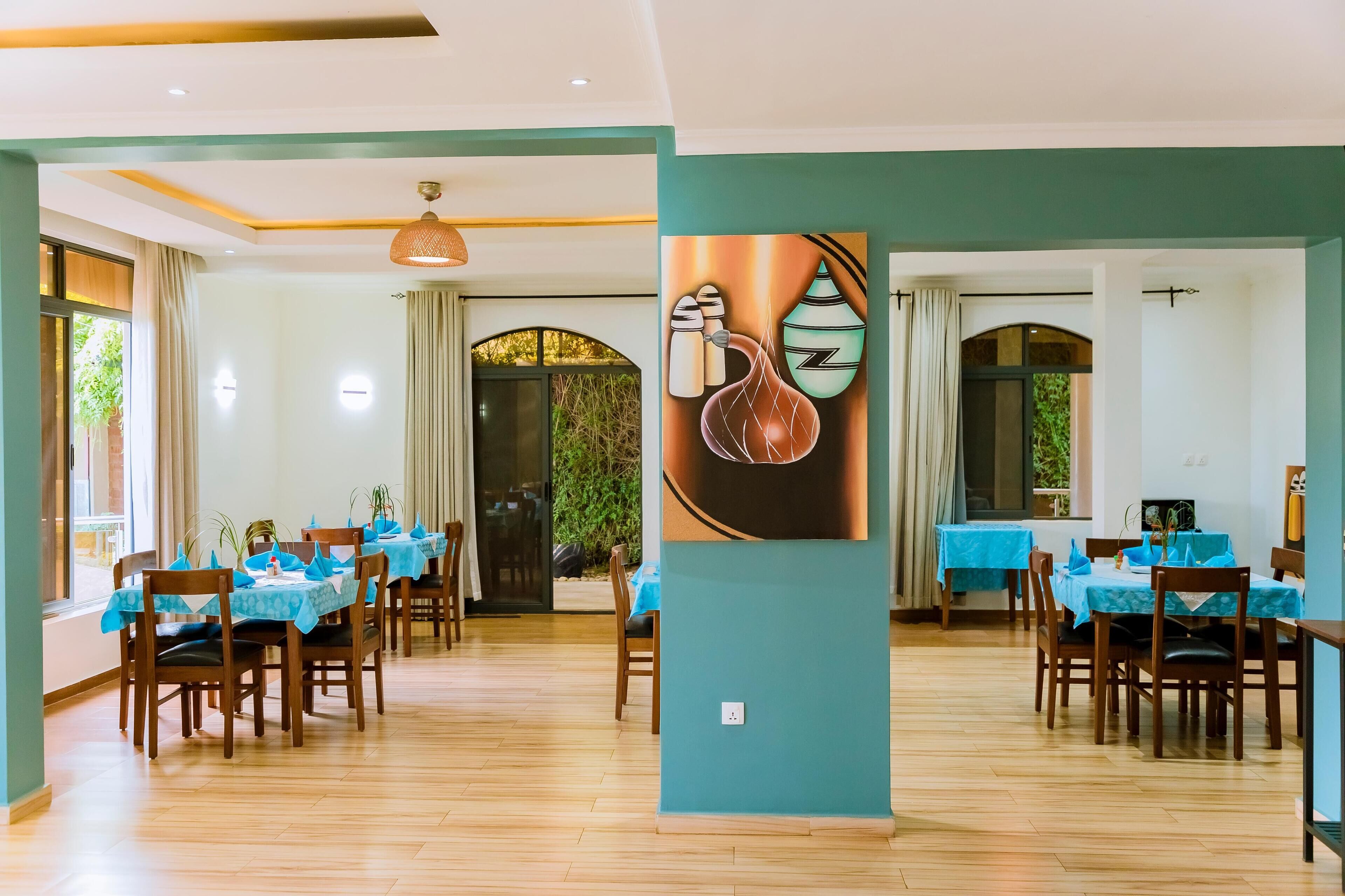 A dining area with tables set for four, wooden chairs, and blue tablecloths.