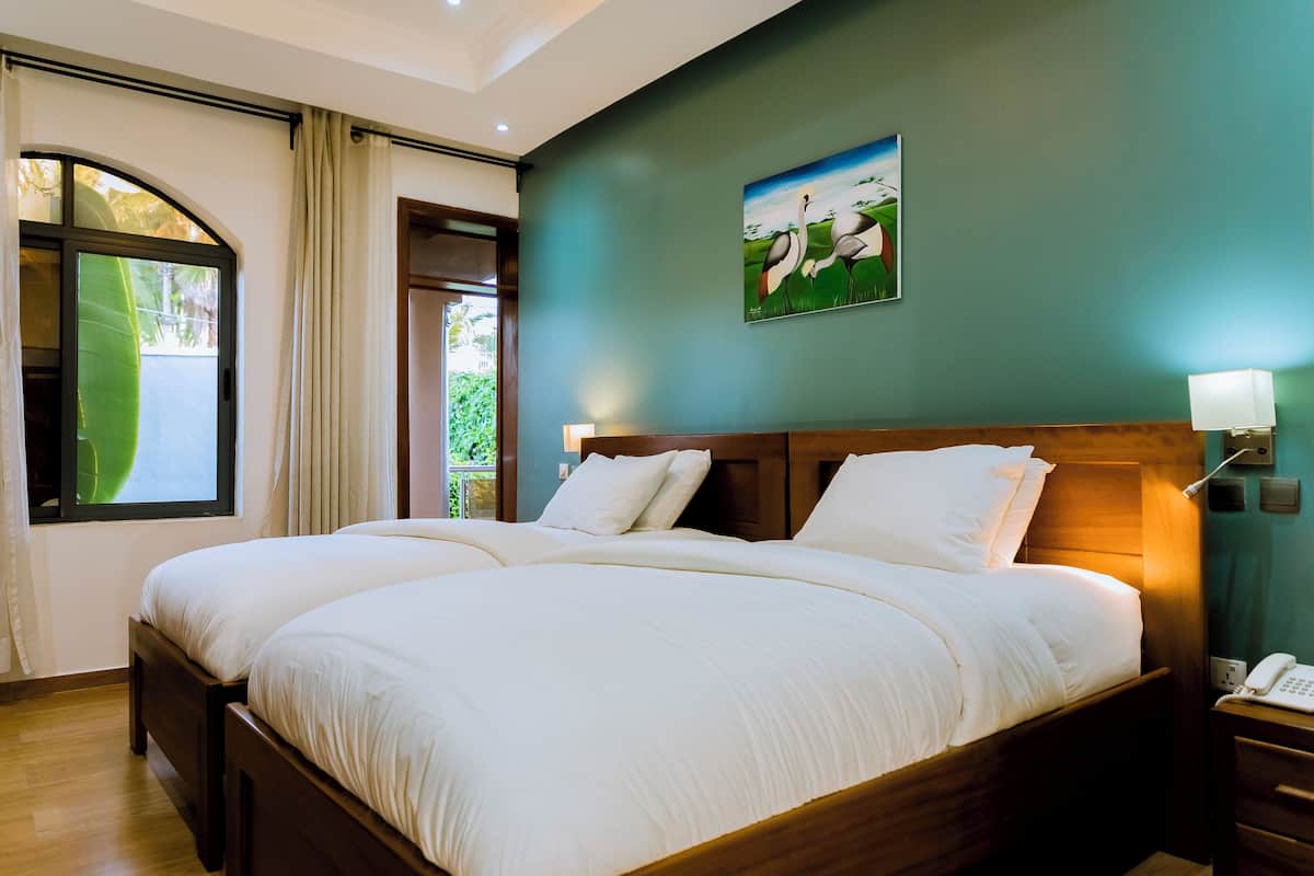 A double bed with white linens, a wooden headboard, and a nightstand with a phone.