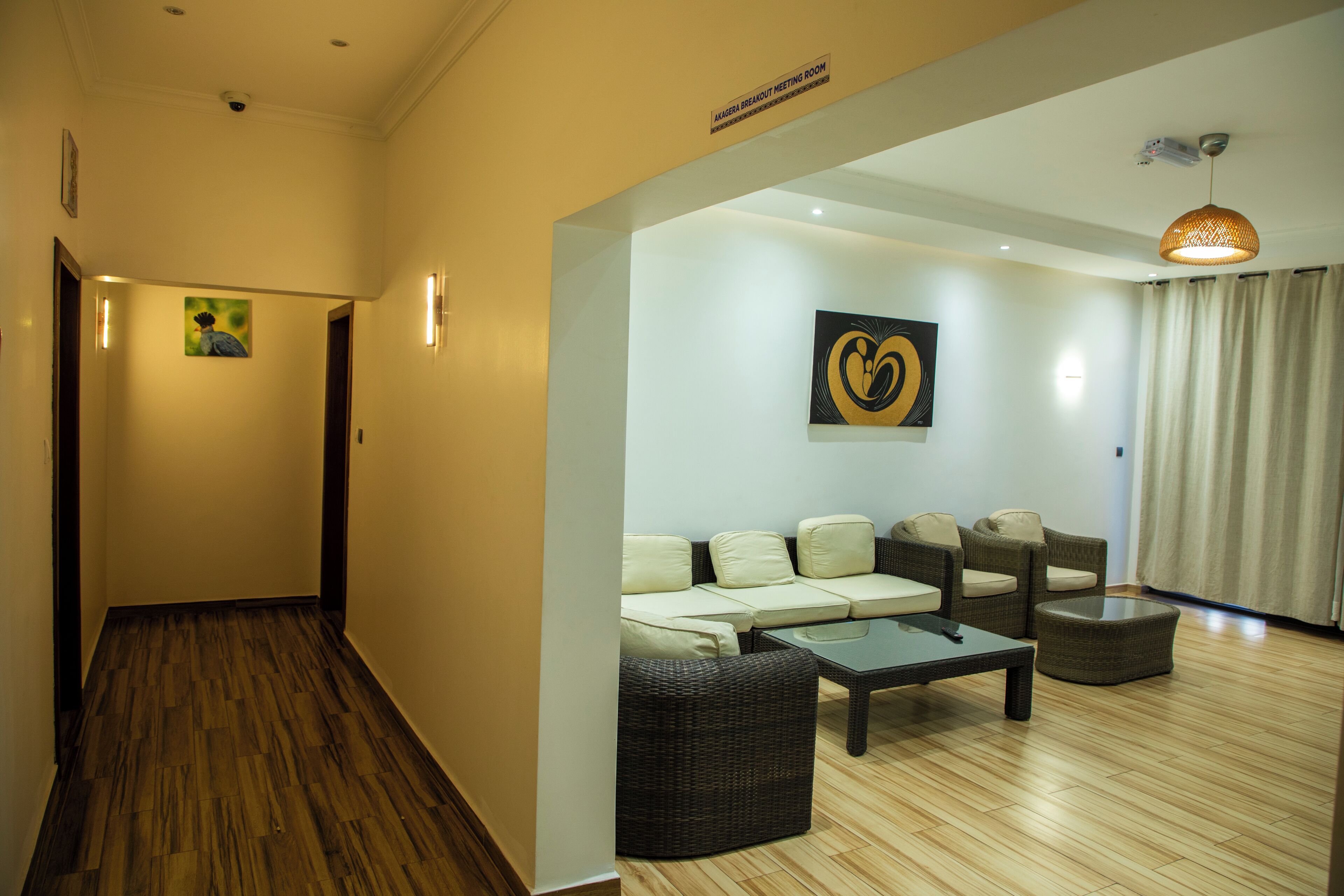 A hotel lobby with a wooden floor, a sofa set, a coffee table, and a painting on the wall.