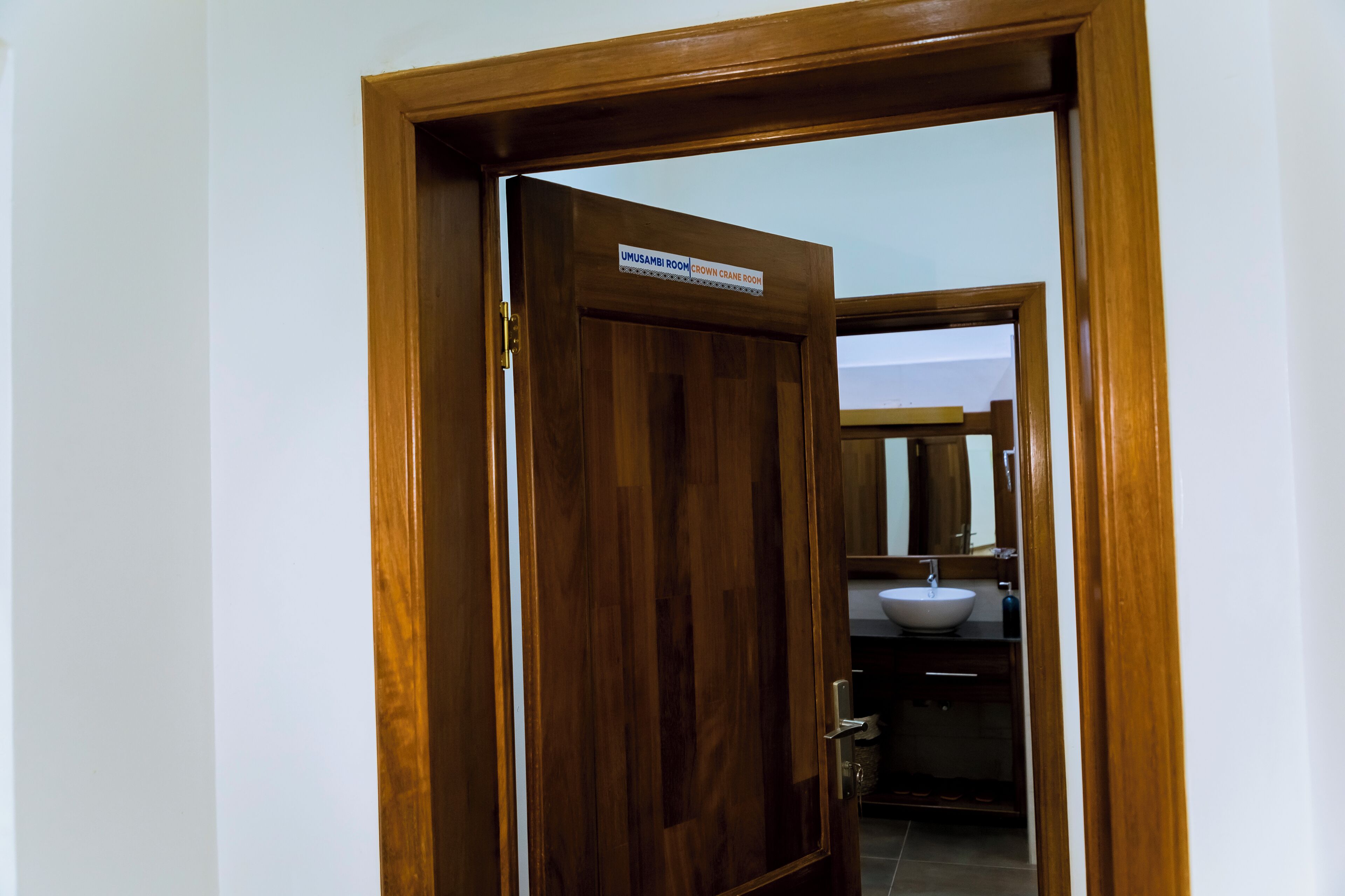 Una puerta de madera con un letrero que dice "UMUSAMBI ROOM BROWN CRANE ROOM".