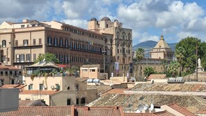 A historic cityscape with traditional architecture, including a prominent church with a dome and a bell tower. - L'ERBA DEI SOVRANI (Palermo)