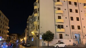 A multi-story building with balconies, a parked car, and a pedestrian crossing. - L'ERBA DEI SOVRANI (Palermo)