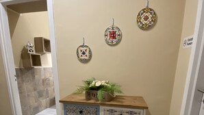 A hallway with a decorative cabinet, a door with a sign, and a tiled wall. - L'ERBA DEI SOVRANI (Palermo)