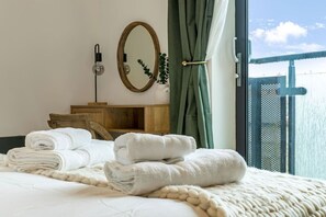 A hotel room with a bed, a wooden cabinet, a mirror, and a view of a bridge. - Central 1BD with Free Underground Parking (Gloucestershire)