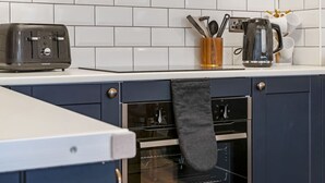 Et køkken med en ristovn, kaffemaskine og elkedel på bordet.