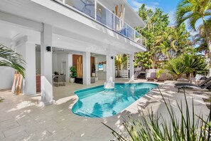 Una casa moderna con piscina, area relax esterna e piante tropicali.
