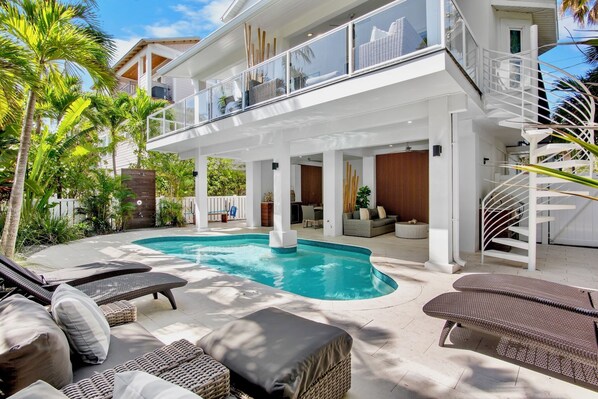 Ein modernes Haus mit Swimmingpool, Sitzgelegenheiten im Freien und einer Treppe.