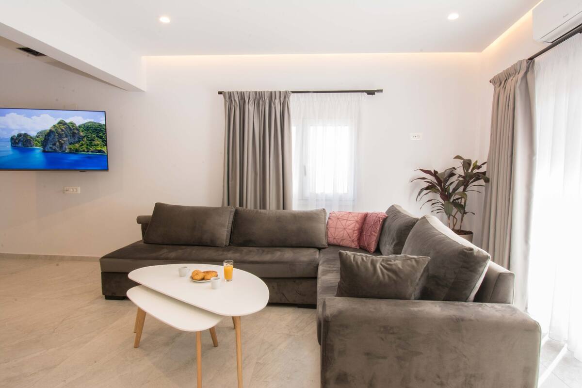 Ein modernes Wohnzimmer mit einem grauen Ecksofa, einem weißen Couchtisch und einem flachbildfernseher, der an der Wand montiert ist.
