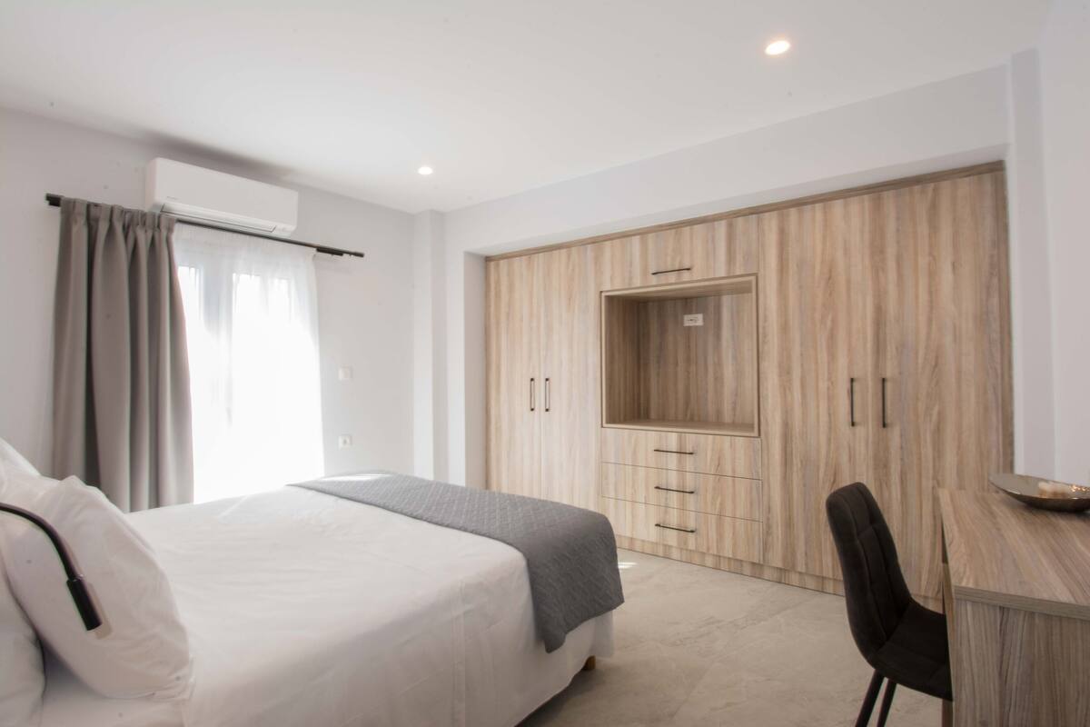 Ein modernes Hotelzimmer mit einem großen Bett, einem Schreibtisch und einem Kleiderschrank mit Spiegel.