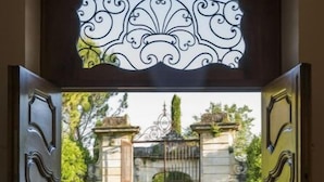An open wooden gate leading to a stone pathway and a building with classical architecture. - Chateau en Provence (Loriol-du-Comtat)