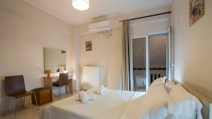 A hotel room with a large bed, a desk with a chair, a radiator, and a window with curtains. - Gianna's House Next To Platanias, 250m From Beach (Platanias)