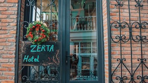 Un edificio de ladrillo con una puerta verde oscuro y un letrero que dice "ZERTA Hotel".