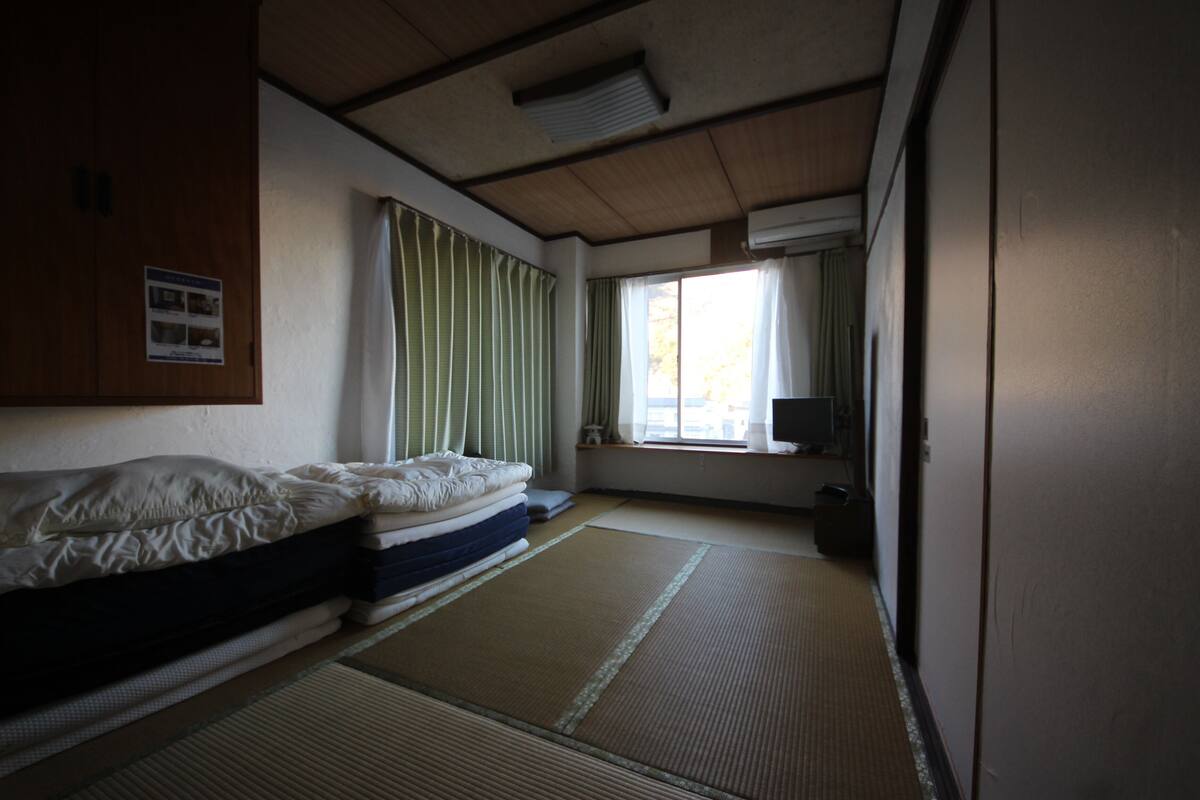 A room with a bed, a television, and a window with curtains.