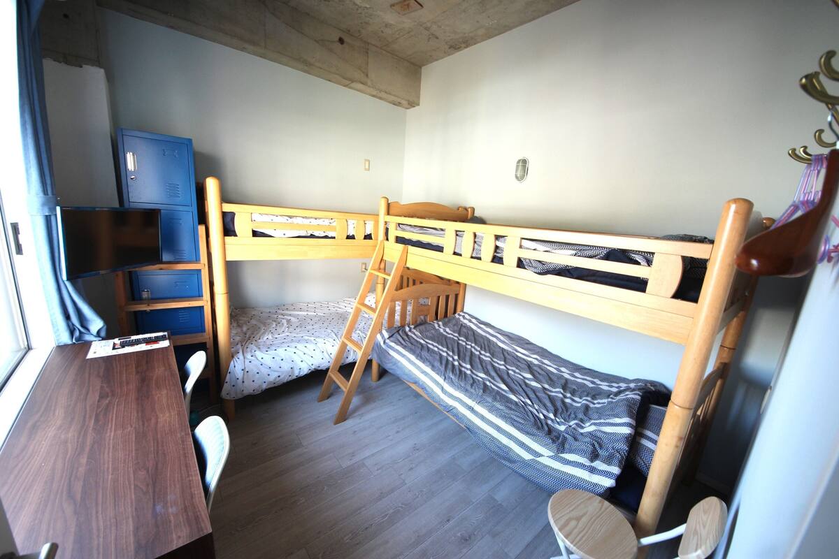 A compact room with bunk beds, a desk, and a chair.