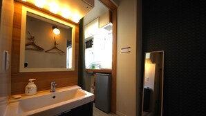 Un baño con lavabo, espejo y perchero.