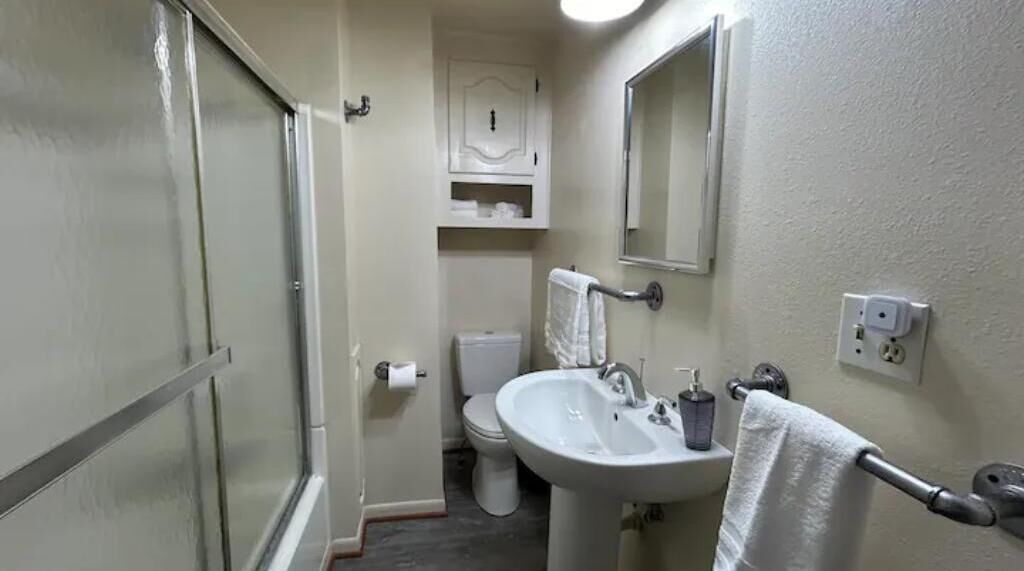 Une petite salle de bain compacte, équipée de toilettes, d’un lavabo et d’un miroir.