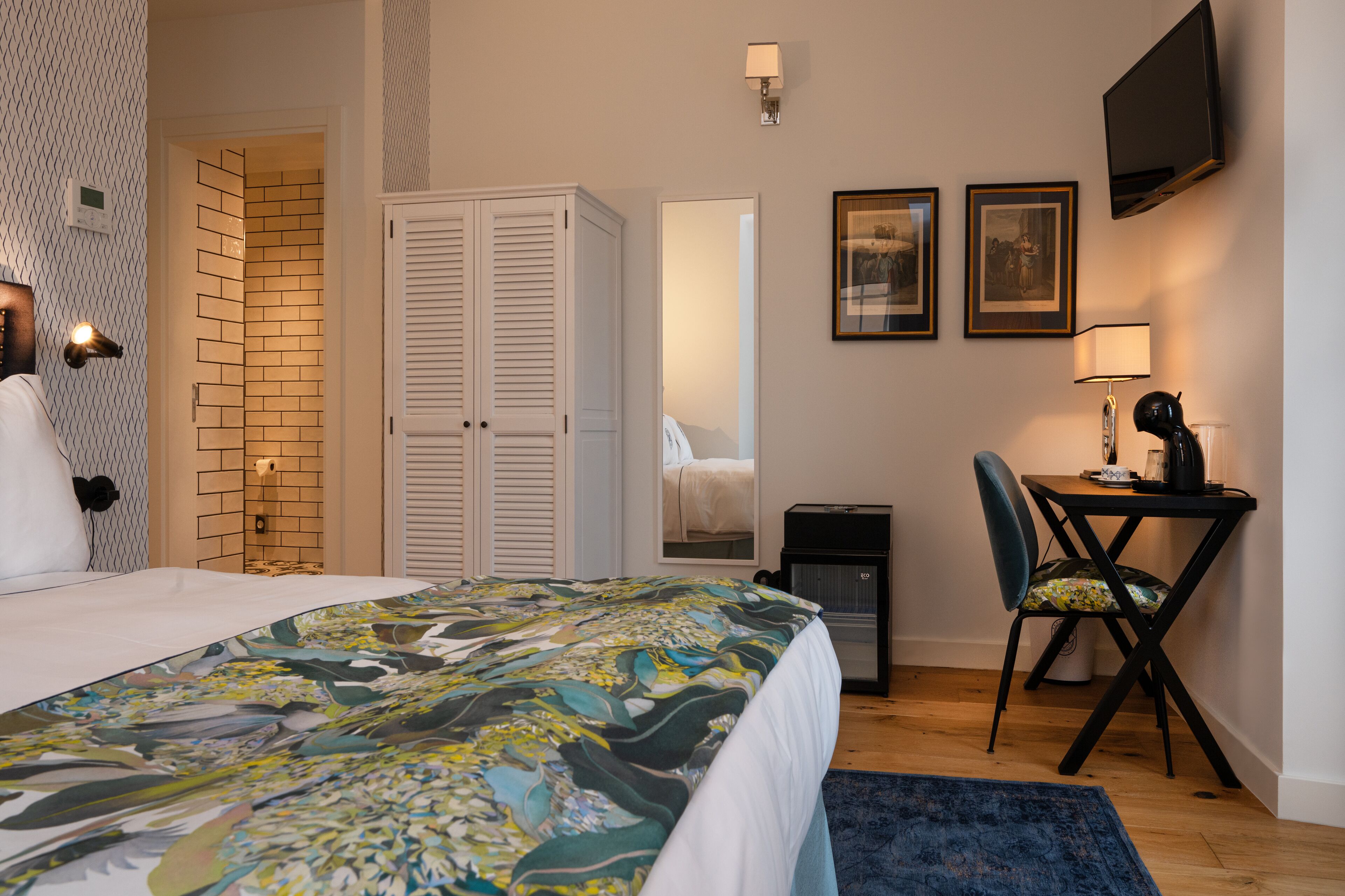 Une chambre d’hôtel avec un lit, un bureau, une chaise, une télévision et un miroir.