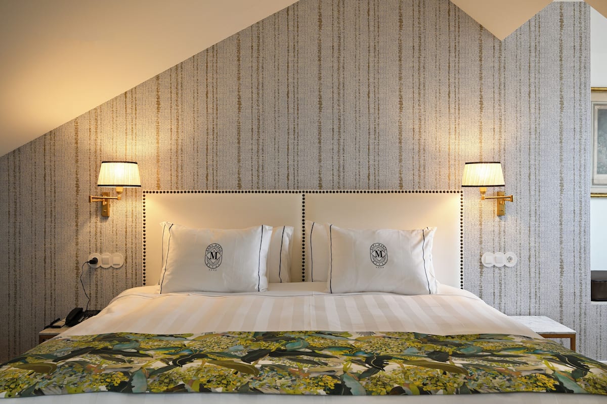 Ein Hotelzimmer mit einem großen Bett, zwei Wandlampen und einem gemusterten Kopfteil.