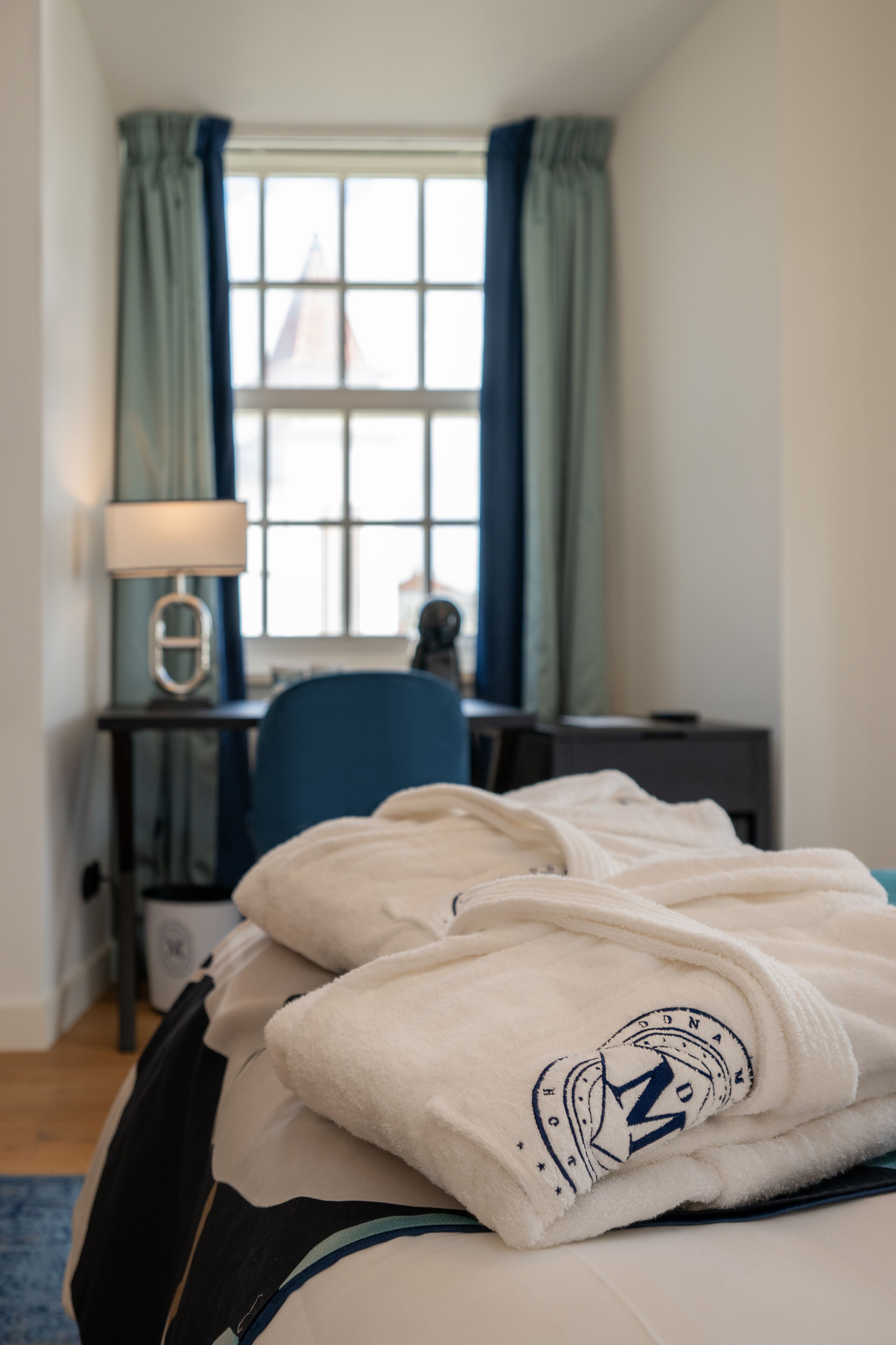 Una camera d'albergo con un letto, una scrivania, una sedia e una finestra con tende.