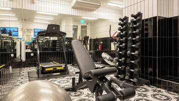 Ein Fitnessstudio mit Trainingsgeräten, einer Spiegelwand und einem gemusterten Boden.