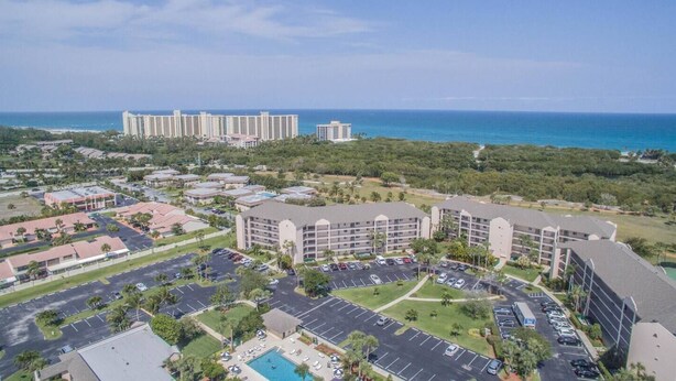 A hotel with multiple buildings, a parking lot, and a view of the ocean. - Jupiter Bay Beach Condo (Jupiter)