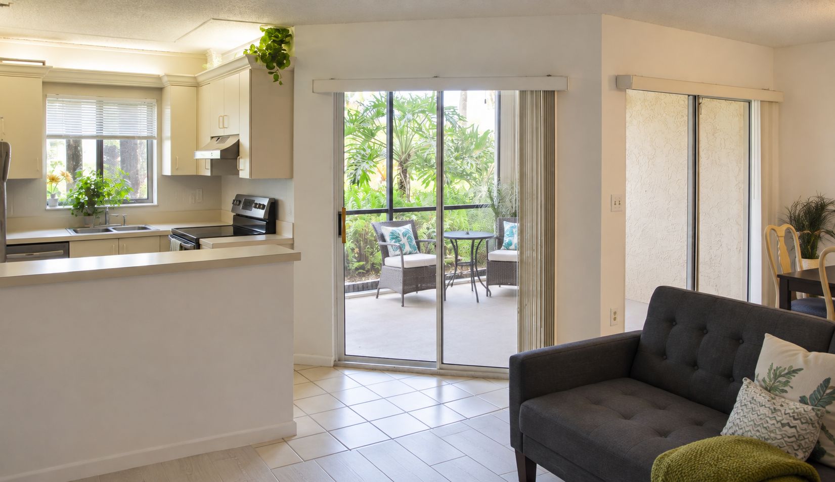 A modern kitchen with a dining area and a sliding glass door leading to a balcony.