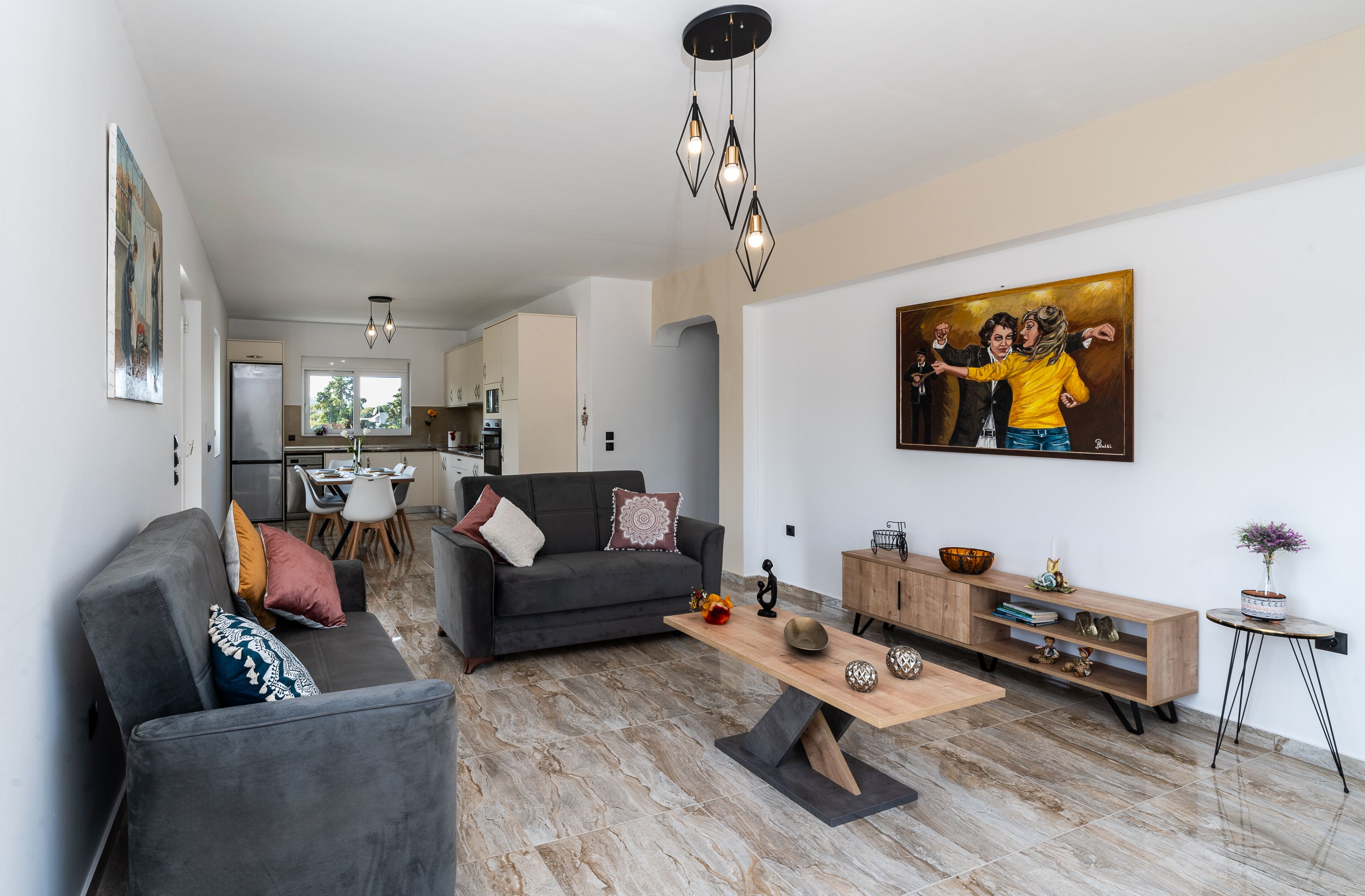 A modern living room with a grey sofa, a coffee table, and a painting on the wall.