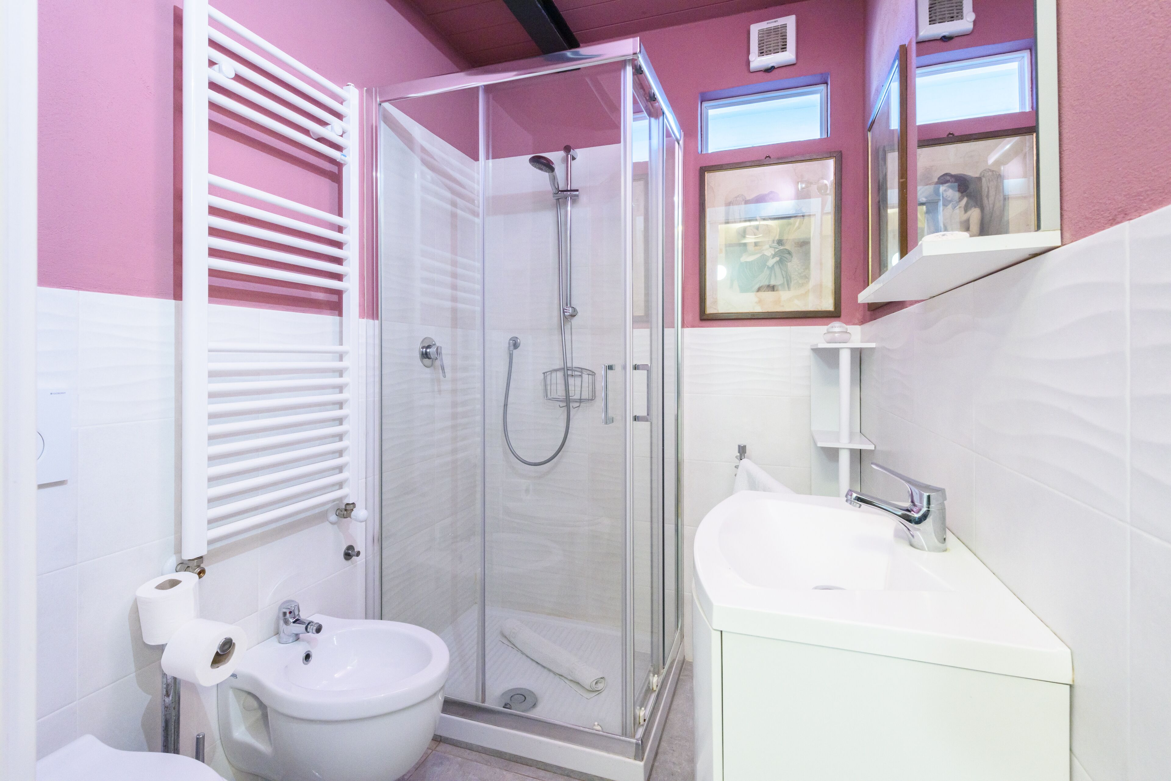 A bathroom with a glass-enclosed shower, a white sink, and a toilet.