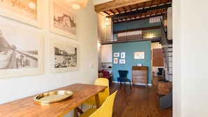 A dining area with a wooden table and yellow chairs, a staircase, and a blue wall with framed pictures. - Terrace on the roof by Mmega (Florence)