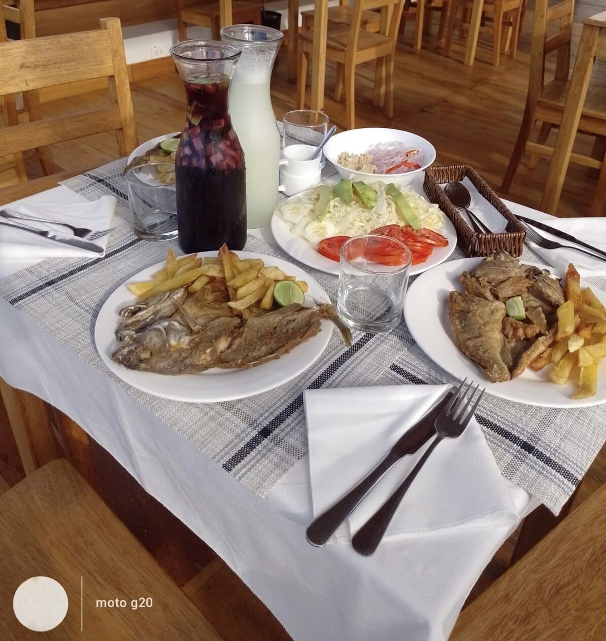 A dining table with plates of food, including fish and fries, and a pitcher of a dark beverage.