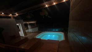 A hot tub area with wooden loungers and string lights. - Punta Veleros Rooftop (Los Organos)