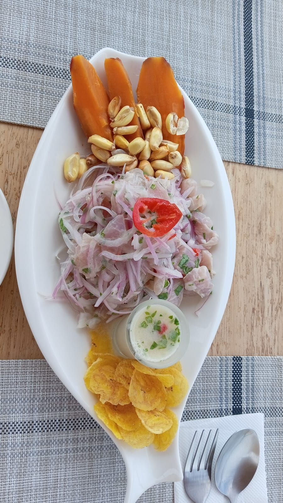 A white plate with a salad, two carrots, peanuts, and chips.