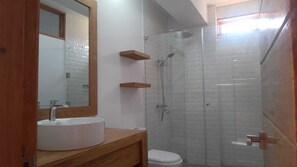A bathroom with a white sink, mirror, and shower enclosure.