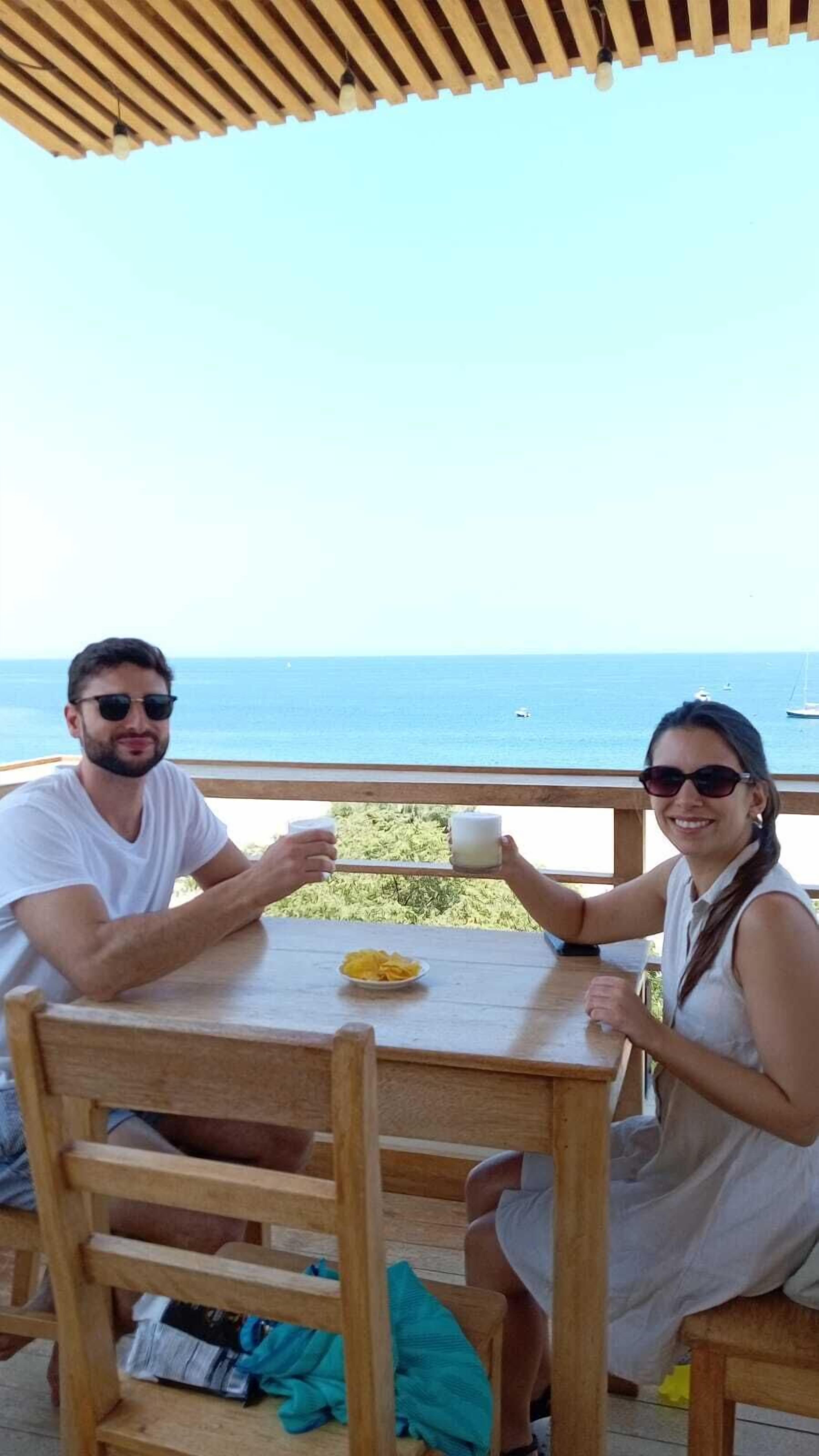 Dos personas sentadas a una mesa de madera con vista al mar.